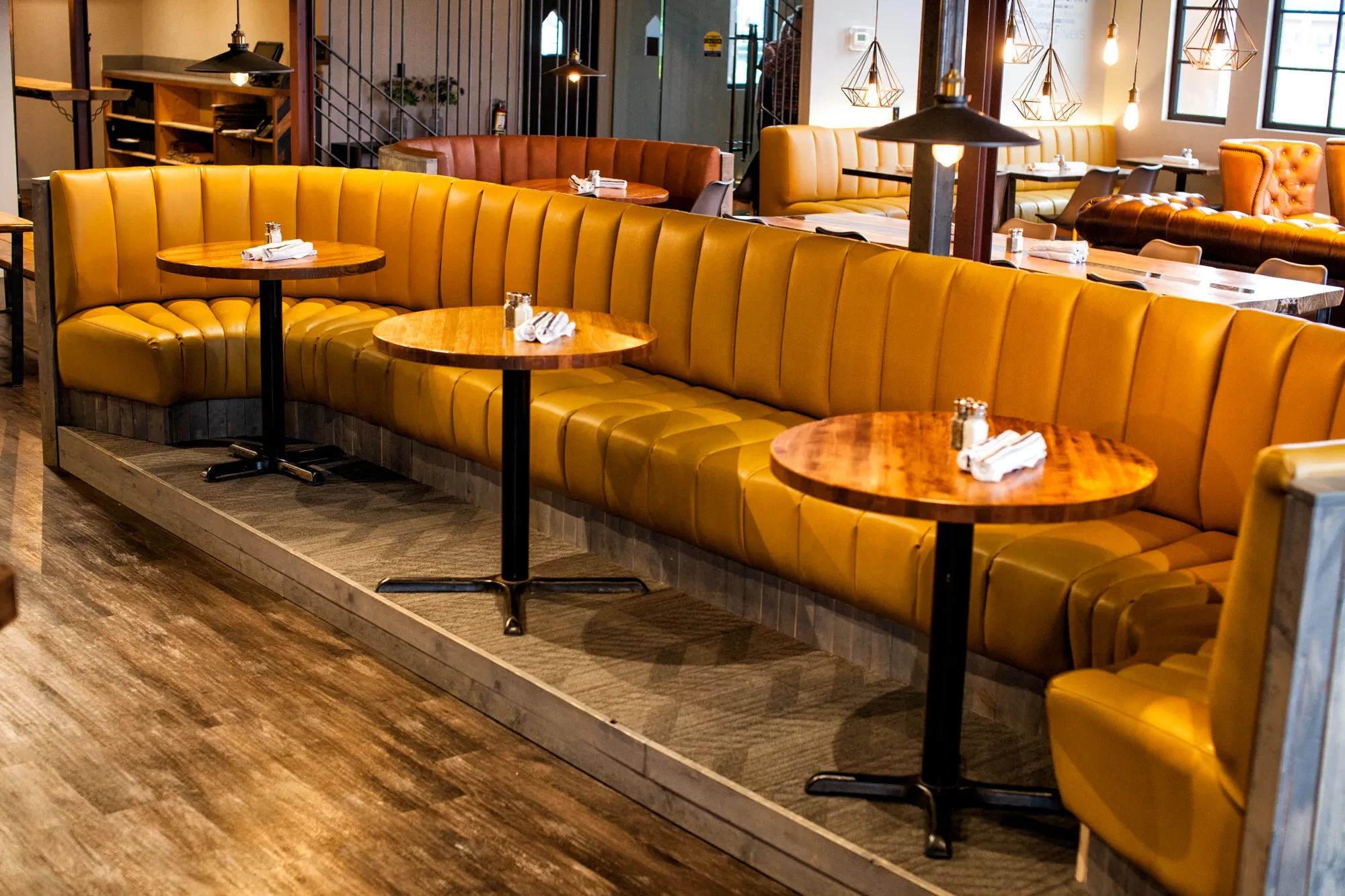 Restaurant interior with amber leather banquette seating and industrial pendant lighting